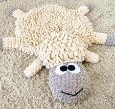 a stuffed sheep laying on top of a carpet covered in fake wool with black eyes