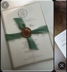 the wedding card has a green ribbon and a wax seal with a tree on it