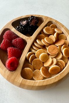 a wooden plate topped with pancakes and raspberries