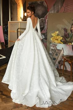 a woman in a white wedding dress standing on a wooden floor with her back to the camera