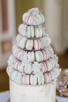 a three tiered cake with macaroons and flowers on the top is decorated in pastel colors