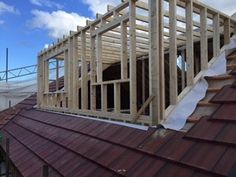 a house being built on top of a roof with wooden framing and metal shingles