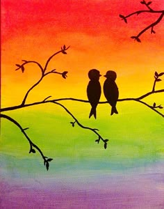 two birds sitting on a tree branch in front of an orange, yellow and green sky