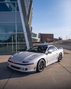 a white sports car parked in front of a large building with glass windows on the side