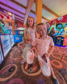 two young children standing next to each other in front of slot machines at an amusement park