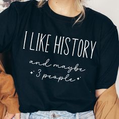 a woman wearing a black shirt that says i like history and maybe 3 people