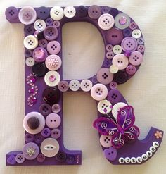 the letter q is made up of buttons and other decorative items, including a butterfly