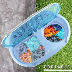 the portable dishwasher is on the grass with its lid open and dishes in it