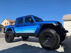 a bright blue jeep parked in front of a house on a sunny day with no one around