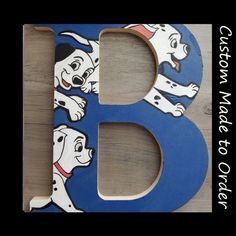 the letter b is made up of wood and has cartoon dogs on it, including a dog