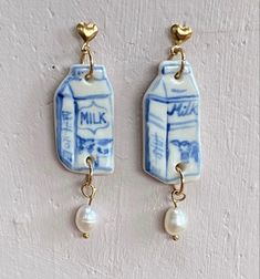 a pair of earrings with milk and pearls hanging from them