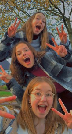 three girls are making the peace sign with their hands