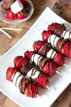 strawberries on skewers with chocolate drizzled over them