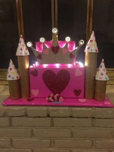 a pink and gold birthday cake with lots of sparkle on it's top, surrounded by little princess crowns