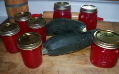 there are many jars with food in them on the table next to some squash and zucchini