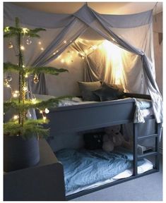 a bed with a canopy over it next to a christmas tree in a room filled with lights