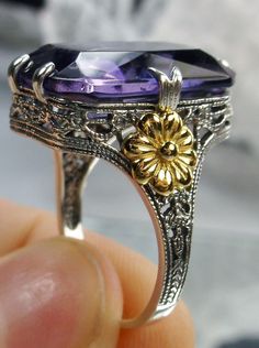 Simulated Amethyst Sterling Silver Ring Gold Daisy#D208 This is a brand-new Vintage revival sterling silver filigree ring. This is a flawless man-made purple amethyst, 18mm by 13mm in size. The ring is 3/4" (19mm) North to South on the finger. Notice the intricate and detailed floral design of the antique patina silver filigree that travels all the way down the band, with a delicate rose gold flower on each side. The inside of the band is marked 925 for sterling silver. This ring has style and c Elegant Rectangular Amethyst Ring For Formal Occasions, Elegant Rectangular Amethyst Ring, Elegant Purple Amethyst Ring With Intricate Design, Exquisite Amethyst Anniversary Ring, Formal Purple Amethyst Ring With Filigree, Exquisite Silver Amethyst Ring, Elegant Purple Amethyst Ring With Filigree, Classic Amethyst Ring With Rectangular Stone For Formal Occasions, Fine Jewelry With Intricate Design In Purple