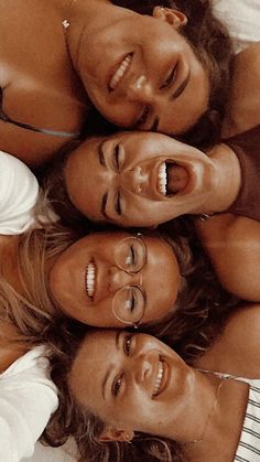 four women are laying in a circle smiling at the camera, with their heads together