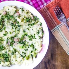 a white bowl filled with pasta and broccoli on top of a wooden table