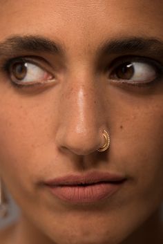 a close up of a person with a nose ring and piercing on their nose looking at the camera