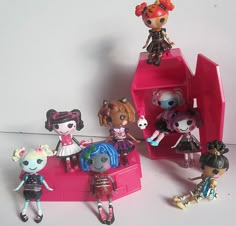 there are many little dolls that are on the toy stand together in this photo, and one is holding a doll