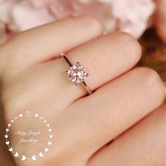 a woman's hand holding a ring with a flower design on the middle and center