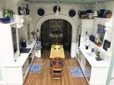 a small kitchen with white cabinets and blue accents on the walls, along with wooden flooring