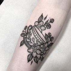 a black and white photo of a tattoo design on the left arm with flowers around it