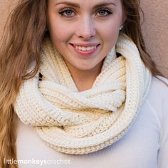 a woman with long hair wearing a white cowl scarf and smiling at the camera