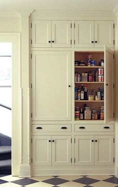 a kitchen with white cabinets and black and white checkered flooring on the floor