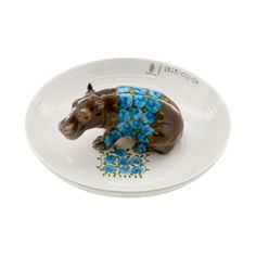 a ceramic rhino figurine sitting on top of a white plate with blue flowers