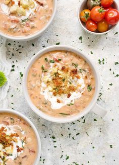 three white bowls filled with soup and topped with sour cream, garnished with fresh herbs