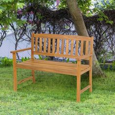 a wooden bench sitting in the grass under a tree