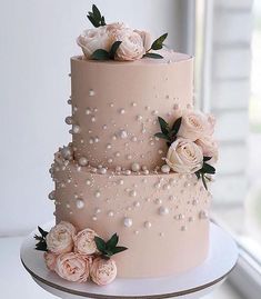 a three tiered pink wedding cake with flowers on top and pearls around the edges