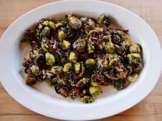 brussel sprouts in a white bowl on top of a wooden table