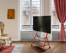 a flat screen tv sitting on top of a stand in a living room next to a chair