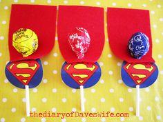 four superman lollipops are sitting on a yellow tablecloth with white polka dots