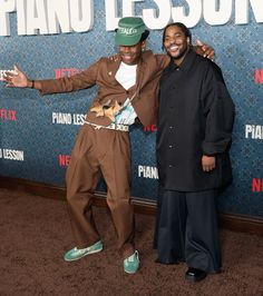 two men standing next to each other in front of a piano lesson sign and posing for the camera