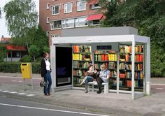 two people are sitting on benches in front of a book store with bookshelves