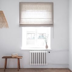 a white room with a wooden table and radiator next to the window in it