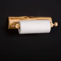 a roll of toilet paper hanging from a wooden holder on a black wall with wood handles