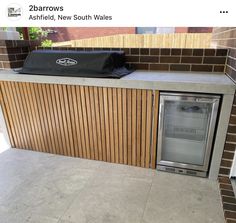 an outdoor bbq grill built into the side of a brick wall with wood slats