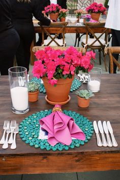 a wooden table topped with pink flowers and plates