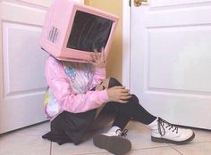 a person sitting on the floor with a pink box on their head