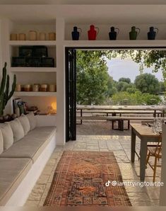 a living room filled with furniture next to a patio covered in plants and potted plants