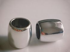 two silver vases sitting next to each other on a white tableclothed surface