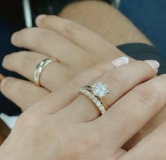 a woman's hand with two wedding rings on her left and the other hand holding an engagement ring