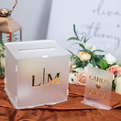 two cards are sitting on a table with flowers and candles in front of the card box