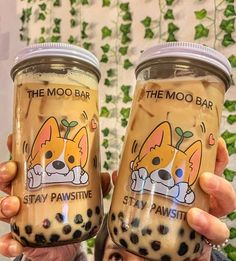 two people holding up cups with the same design on them, one has a dog in it