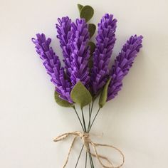 purple flowers are tied up on a white surface